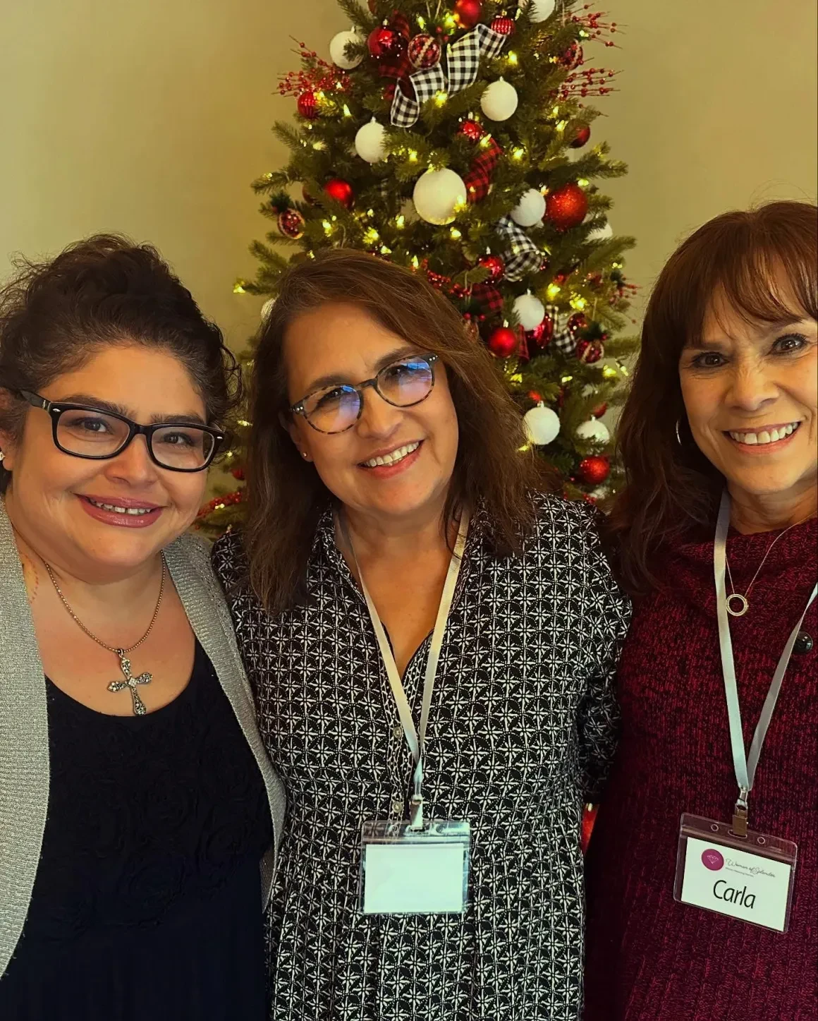 Three women smiling by Christmas tree