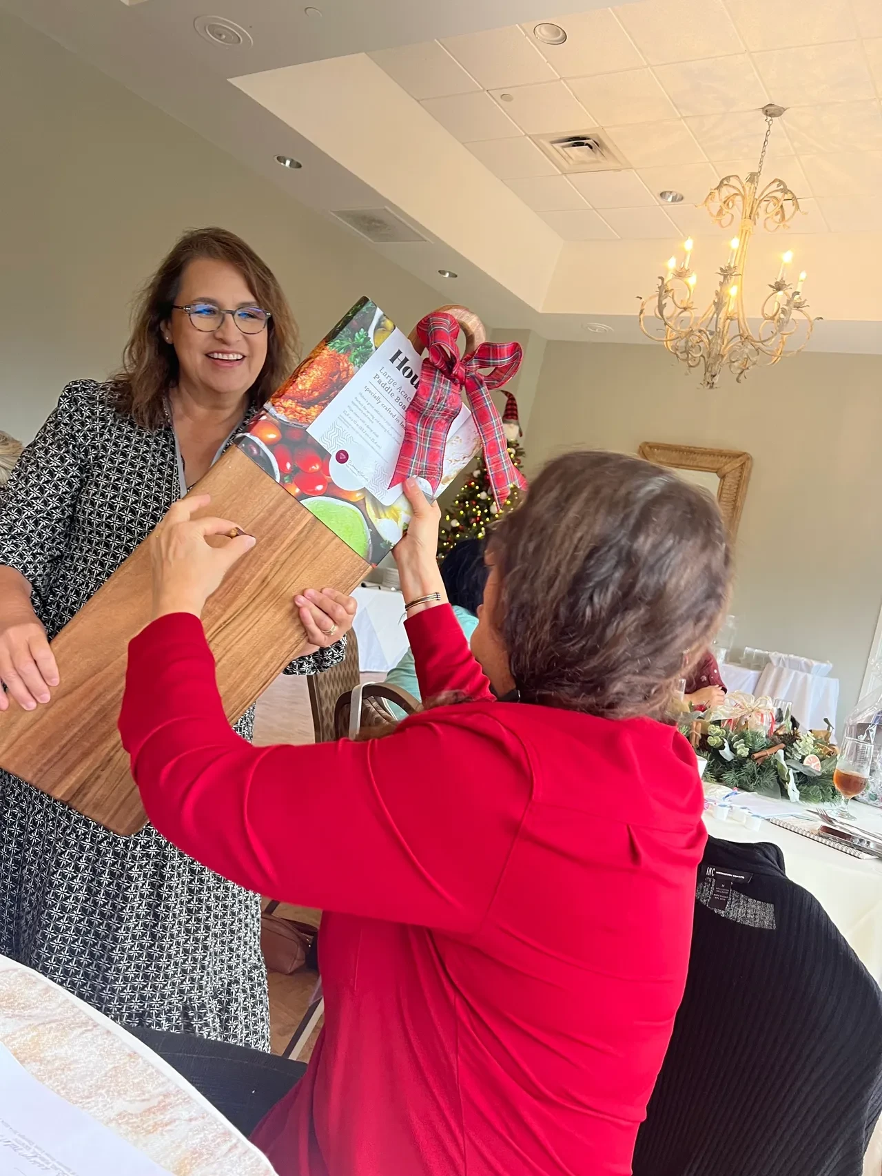 Two women exchanging holiday gift at event
