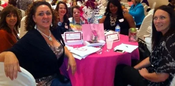 Women smiling at pink-themed event table