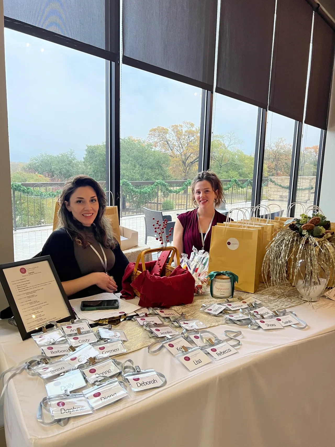 Two women at registration table with name badges and gift bags